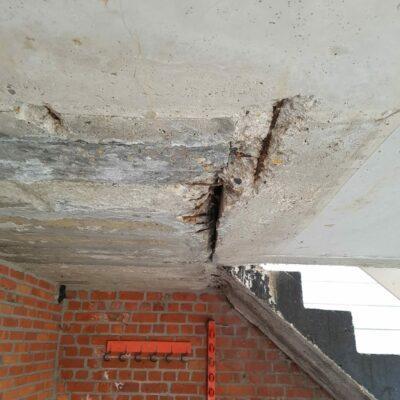 Plafond van balkon. beschadigd beton. Verroeste bewapening. Bros beton. Deels uitgekapt.